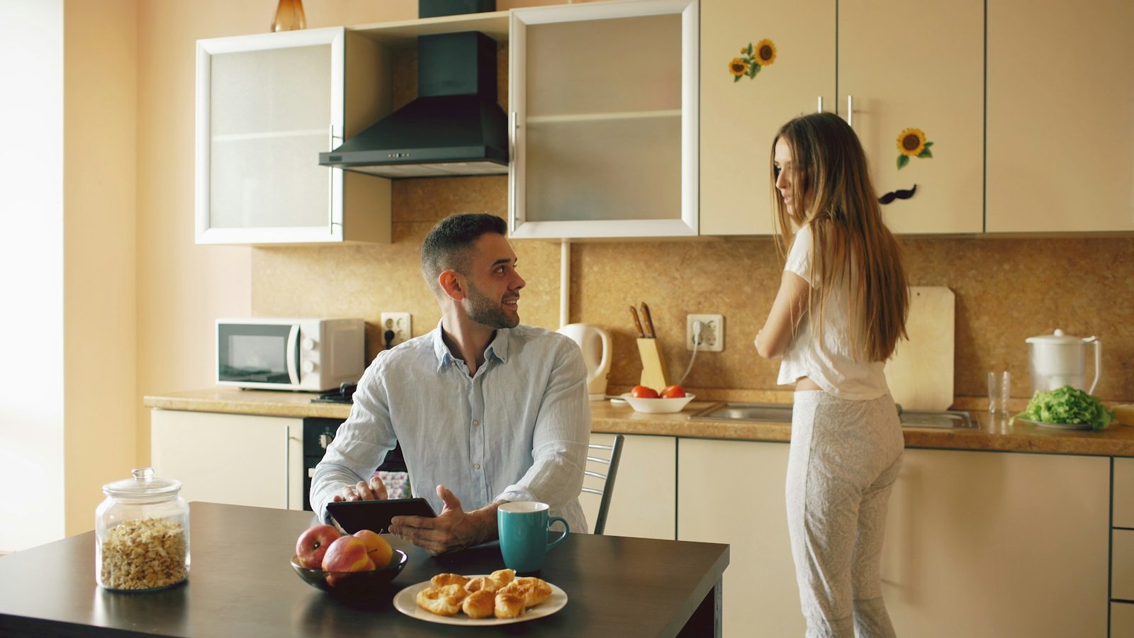 A couple talking at a kitchen table over breakfast