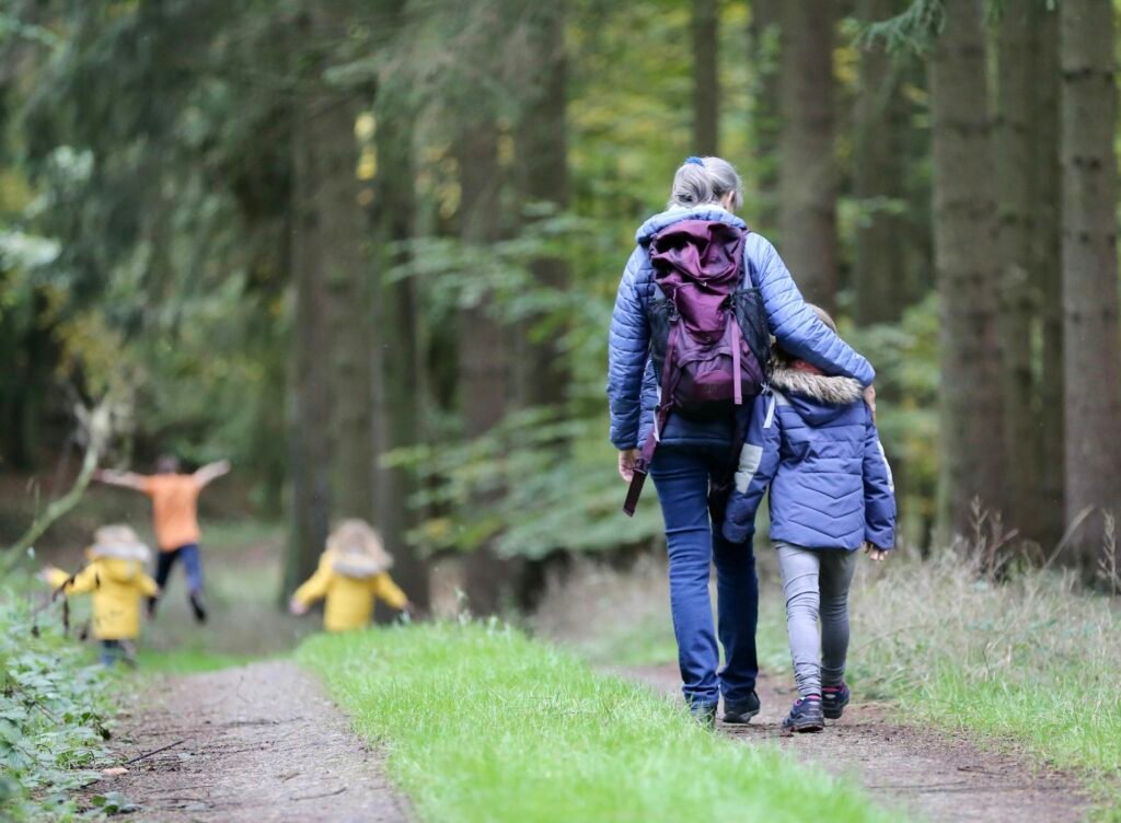 Two adults and three children walking together along a path through the woods